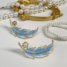 This exquisite piece features a meticulously crafted feather design, adorned with lustrous pearls, evoking the serene beauty of swans gliding across a tranquil lake. A symbol of elegance and grace, it's perfect for adding a touch of sophistication to any outfit. Composition: enamel, pearls, zircon, gold-plated brass Avoid exposure to harsh chemicals, such as perfume, hairspray, and cleaning agents. Store your metal jewelry in a dry and cool place to prevent tarnishing. Use a soft cloth to gently clean your jewelry after each wear to remove dirt and sweat. If your jewelry becomes tarnished, use a specialized cleaning solution or a mixture of baking soda and water to remove it. Avoid wearing metal jewelry when swimming or showering to prevent damage. Remove your jewelry before exercising or Swan Brooch, Forever Jewelry, Feather Design, Swan Lake, Pearl Brooch, Jewelry Ring Box, Mens Jewelry Bracelet, Swans, Watch Necklace