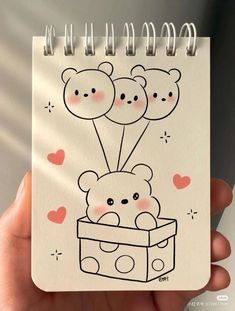 a hand holding a notebook with an image of two teddy bears in a box