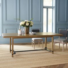 a dining table with two chairs and a vase filled with flowers