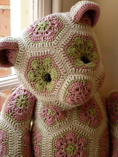 a crocheted teddy bear sitting in front of a window