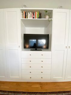 a flat screen tv sitting on top of a white wall mounted entertainment center in a living room