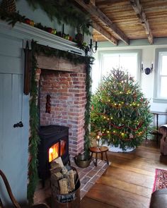 a living room filled with furniture and a fire place next to a christmas tree on top of a fireplace