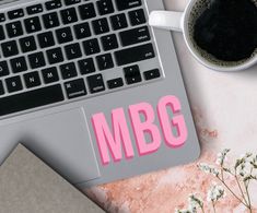 a laptop computer sitting on top of a desk next to a cup of coffee and flowers