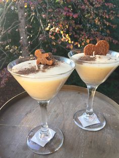 two glasses filled with dessert sitting on top of a wooden table