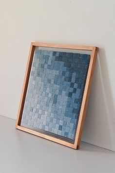 a wooden frame holding a blue mosaic tile pattern on the inside of it, against a white wall