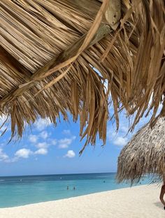 the beach is covered with straw umbrellas and people are swimming in the blue water