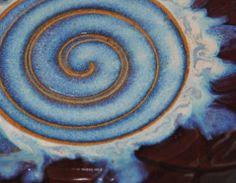 a blue and yellow plate with swirls on it's surface, sitting on a table