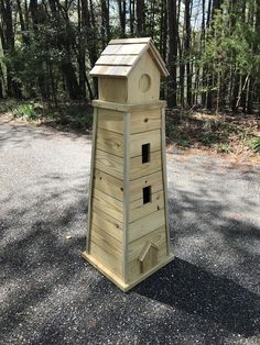 a wooden bird house sitting on top of a gravel road