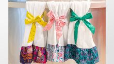 four different colored bow ties hanging on the side of a window sill in front of curtains