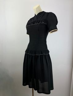 Cute 1940'S black rayon dress with a fitted bodice and a drop waist. There is this pleated flouncy trim that lines the chest and wraps around the drop waist. There is an attached belt that ties in the back. Super sweet. The sleeves are short and puffy. There is a metal talon side zipper as well as 4 cloth covered buttons in back along the neckline. The skirt is rather short and flirty, which reminds me of cute baby doll dresses. This dress is in EXCELLENT VINTAGE CONDITION... no real issues to p Puffy Sleeve Dress Vintage, Dropped Waist Dress, Puffy Sleeve Dress, Vintage 90s Dress, Flare Shirt, Vintage Party Dresses, Fitting Room, Drop Waist Dress, Dress Fitted