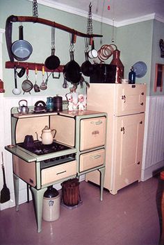 an old fashioned stove with pots and pans hanging on the wall