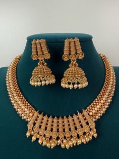 This exquisite piece of craftsmanship comes from our Traditional collection. Finish: 24 grams gold finish Necklace Fastening: Adjustable Dori  Perfect for Indian weddings. Earring jhumka Fastening: Push Back Contains: 1 necklace, 1 pair of earrings Luxury Gold Temple Necklace With Peacock Design, Luxury Temple Necklace With Peacock Design For Festivals, Gold Chandbali Temple Jewelry Necklace, Filigree Chandbali Necklace As A Gift, Chandbali Filigree Necklace As A Gift, Chandbali Filigree Necklace Perfect As A Gift, Gold Temple Jewelry Sets With Tilla, Bridal Brass Necklace With Intricate Design For Celebration, Elegant Gold Bridal Necklace For Rituals