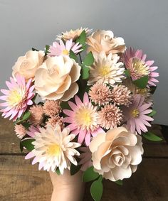 a vase filled with lots of pink and white flowers on top of a wooden table