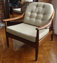 a chair sitting in front of a mirror on top of a hard wood floor next to a brick wall