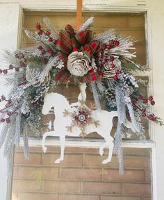 a christmas wreath hanging on the side of a building with a horse and snowflakes