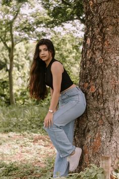 a woman leaning against a tree in the woods