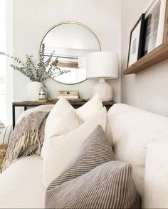 a living room filled with lots of white furniture and pillows on top of a couch