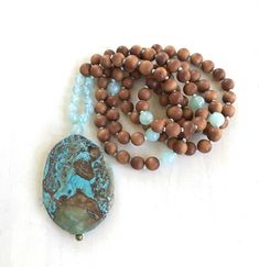 "Tranquility Mala Beads - Ocean Jasper & Sandalwood Beads - Hand Knotted - 108 Bead Mala - Length approx. 40\" The rhythmic cadence of the sea has always called humanity to its shores. This Ocean Jasper and Sandalwood Mala bead necklace from True Nature Jewelry brings that same spirit of peace and letting go. Hand knotted for flexibility and beauty, it features soothing and fragrant Sandalwood beads and Light Aqua Agate to help balance the emotions. A large Ocean Jasper pendant which brings Turquoise Spiritual Beads For Meditation, Spiritual Turquoise Beads For Meditation, Meditation Beaded Necklace With Natural Stones, Artisan Wooden Beads For Meditation, Artisan Wooden Meditation Beads, Earthy Wooden Beads As A Gift, Spiritual Turquoise Necklace With Wooden Beads, Spiritual Turquoise Necklaces With Wooden Beads, Spiritual Beaded Necklaces With Oval Beads For Beach