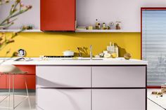 a kitchen with red and yellow cabinets, white counter tops and stools