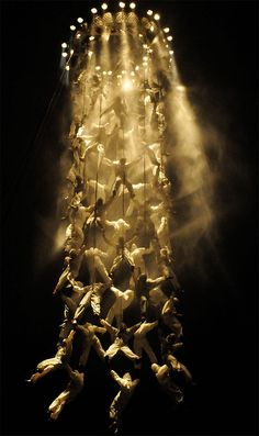 a group of people hanging upside down in the air with lights coming from behind them