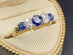 three blue and white stones sit in a gold ring box on top of a black surface