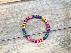 a multicolored beaded bracelet sitting on top of a wooden table