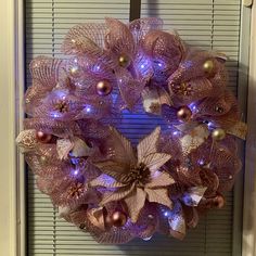 a wreath with purple and gold decorations on the front door, hanging from a window sill