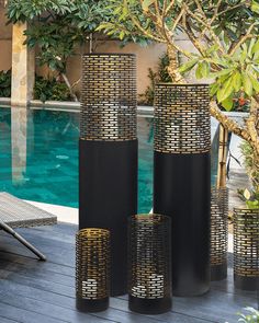 four tall black vases sitting next to a swimming pool