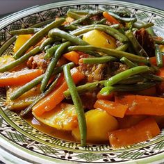 a plate full of food with green beans and carrots on it's side