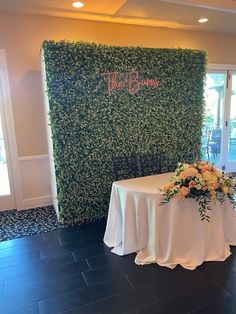 a table is set up in front of a green wall with the words the garden on it