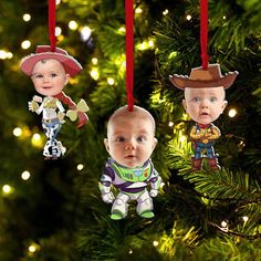 three ornament shaped like baby's heads hanging from a christmas tree