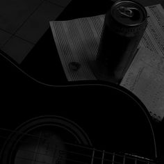 a black and white photo of an acoustic guitar with a can of soda on it