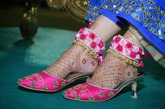 the feet and ankles of a woman wearing pink shoes with floral decorations on their legs