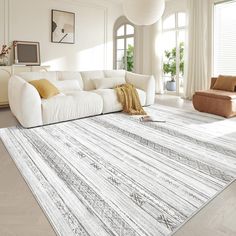 a large white couch sitting on top of a rug in a living room next to a window