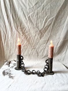 two candles are chained to each other on a white surface with a chain around them