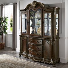 an ornate china cabinet with glass doors and gold trimmings in a living room