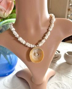 Dive into summer elegance with our exquisite necklace, a harmonious blend of white seashell chips, lustrous white freshwater pearls, and sparkling Charlotte-cut Czech glass beads. At its heart lies a stunning limpet shell adorned with a captivating white freshwater pearl centerpiece. Measuring approximately 40 cm (16 inches) with a 5 cm extension chain, this one-of-a-kind (OOAK) piece captures the allure of the oceanic theme and is perfectly on-trend for the summer of 2024.  Whether you're dress Handmade White Pearl Shell Necklace, White Shell-shaped Jewelry With Pearl Pendant, Handmade White Shell-shaped Pearl Necklace, Mother Of Pearl Shell Strand As Gift, Mother Of Pearl Shell Strand Gift, Pearl White Mother Of Pearl Shell Necklace Gift, Pearl White Mother Of Pearl Shell Necklace As Gift, White Shell Necklace With Pearl Charm For Vacation, White Shell-shaped Pearl Drop Necklace