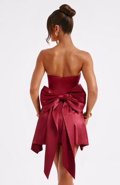 The Freja mini dress is party perfection. Crafted in luxurious stretch satin, this beautiful design is strapless with a corseted bodice and flirty, flouncy skirt. A dramatic bow to the back finishes the look.   Colour: Burgundy. Luxury stretch satin. Oversized bow to back. *Detachable.  Strapless. Corset body. Zip fastening to reverse. Mini length. Model is an XS and is wearing an XS. Homecoming Dresses Corset, Midi Dress Wedding Guest, Burgundy Mini Dress, Long Sleeve Homecoming Dresses, Homecoming Dresses Long, Maxi Dress Sale, Sparkle Dress, Dresses By Length, Stretch Satin