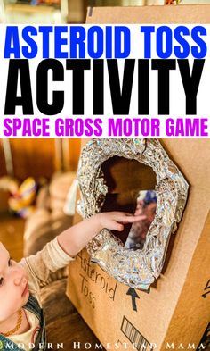 a young child playing with an object in a cardboard box that says asteroid toss activity space gross motor game