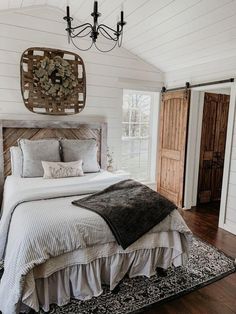 a bedroom with white walls and wood flooring has a large bed in the center