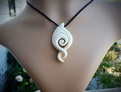 a white necklace on a mannequin neck with an intricate design in the center