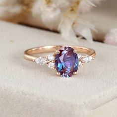 a ring with a large purple stone surrounded by small white stones on top of it