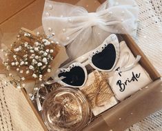 an open box with sunglasses, flowers and bride's t - shirt in it