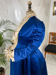 Very rare pregnancy or maternity dress, ca. 1890. Origin: America. According to the way it was made, the dress is a home dress, which was not intended for the looks of outsiders. The dress is made of royal blue satin. Is a one-piece, but tailored to give the impression that it consists of two parts. Breast insert made of cream silk. Pleated "snipe". The sleeves (underarm) are made of the same silk. Ruffles at the neckline and cuffs. The hem of the dress is pleated. The skirt falls in a bell shap Victorian Maternity Dress, Blue Victorian Dress With Historical Design, Blue Regency Style Victorian Dress, Fitted Historical Victorian Ball Gown, Victorian Blue Dresses With Historical Design, Victorian Ball Gown With Historical Design, Victorian Gown With Ruffles And Fitted Style, Victorian Fitted Gown With Ruffles, Blue Victorian Dress For Costume Events