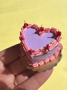 a small heart shaped cake sitting on top of a piece of paper in someone's hand