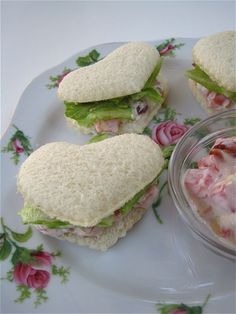 three sandwiches on a plate with a bowl of salad in the middle next to it