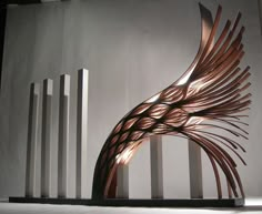 an artistic sculpture is displayed in front of a white wall with columns and lines on it