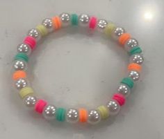 a bracelet with multi colored beads and silver balls on it's end, sitting on a white surface