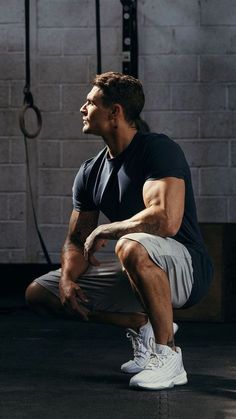 a man squatting on the ground in a gym