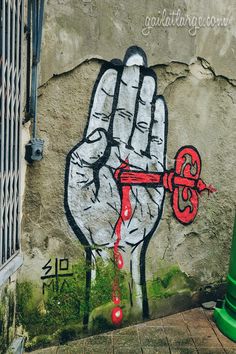 a hand painted on the side of a building with a red key hanging from it